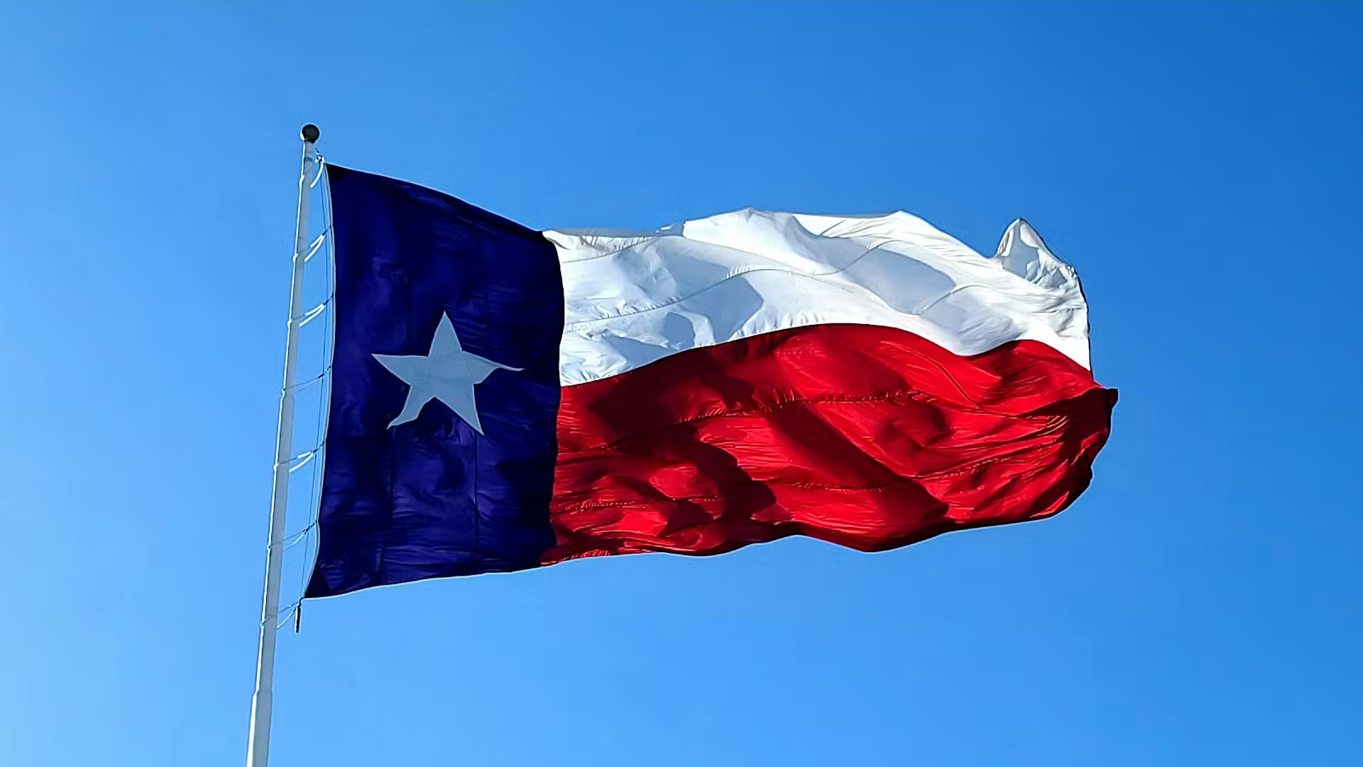 Texas flag waving against a clear blue sky